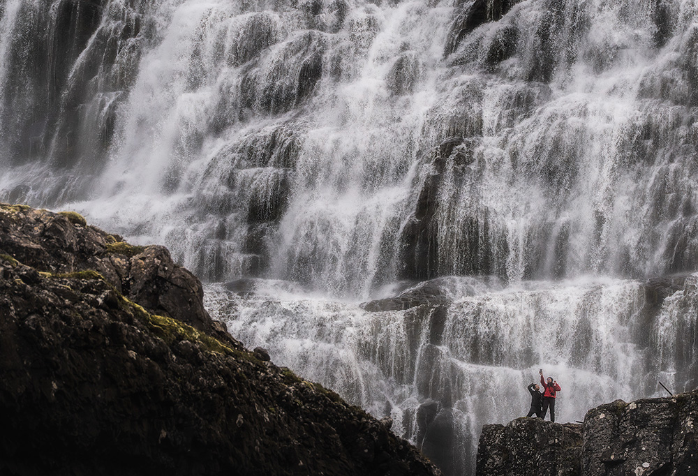 A couple beneath Dynjandi, one of Iceland's largest waterfalls