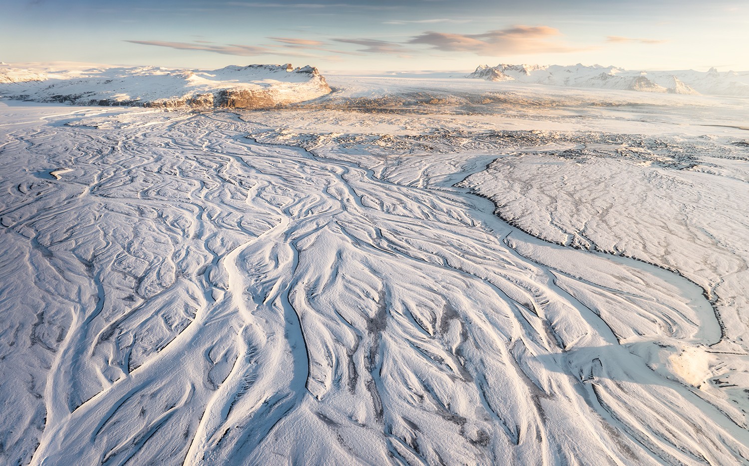 Veduta aerea di una pianura innevata solcata dai canali di un fiume intrecciato.