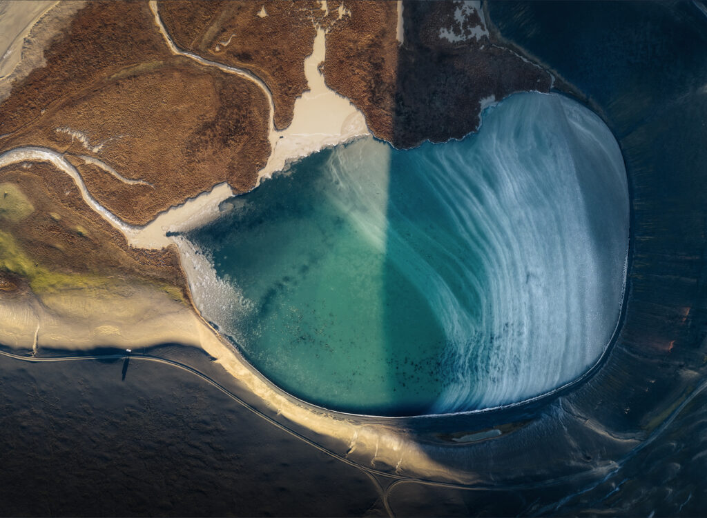 Veduta aerea di una laguna glaciale turchese tra terreno vulcanico, negli altipiani islandesi.